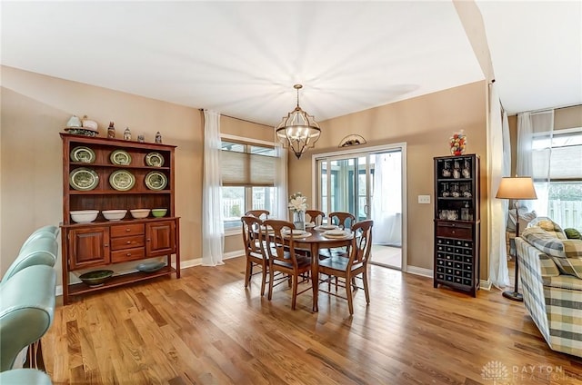 dining space featuring baseboards, a chandelier, and wood finished floors