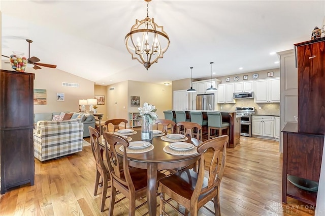 dining space with lofted ceiling, light wood-style flooring, recessed lighting, ceiling fan with notable chandelier, and visible vents