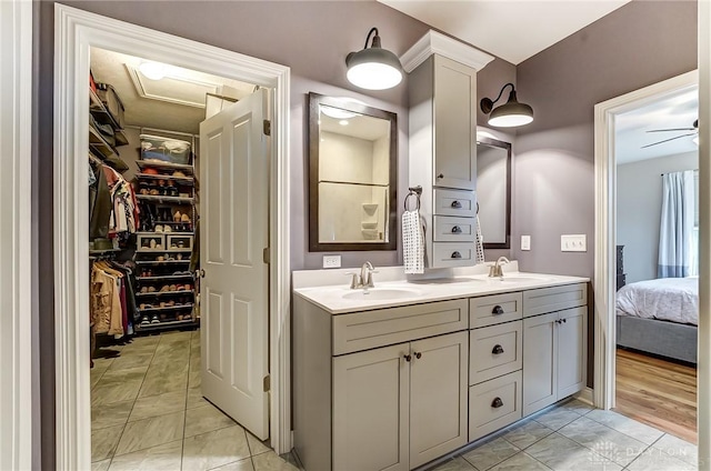 bathroom featuring double vanity, a sink, a walk in closet, and tile patterned floors