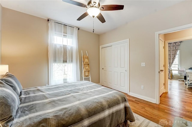 bedroom with light wood-style floors, a closet, baseboards, and a ceiling fan