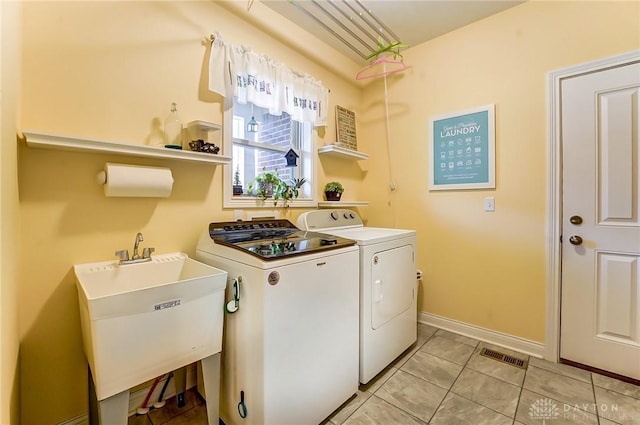 clothes washing area featuring laundry area, light tile patterned floors, visible vents, washing machine and dryer, and a sink