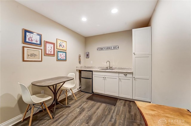 bar with refrigerator, a sink, baseboards, wet bar, and dark wood-style floors