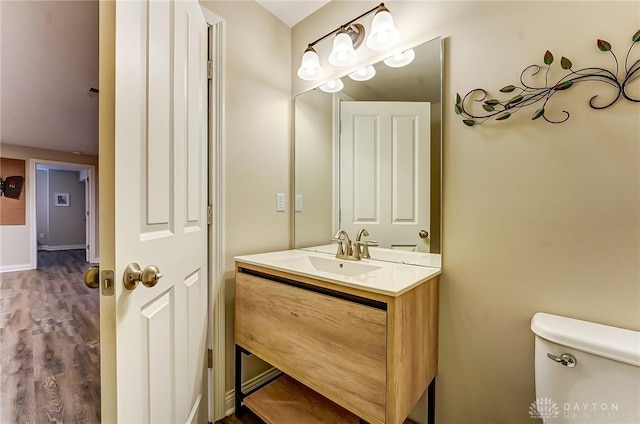 half bath with vanity, toilet, and wood finished floors