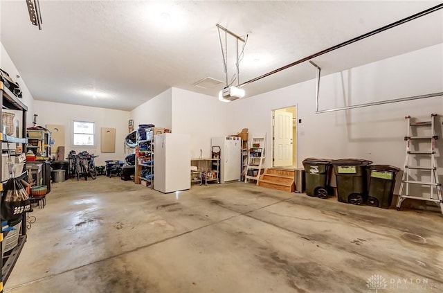 garage featuring electric panel, freestanding refrigerator, and a garage door opener