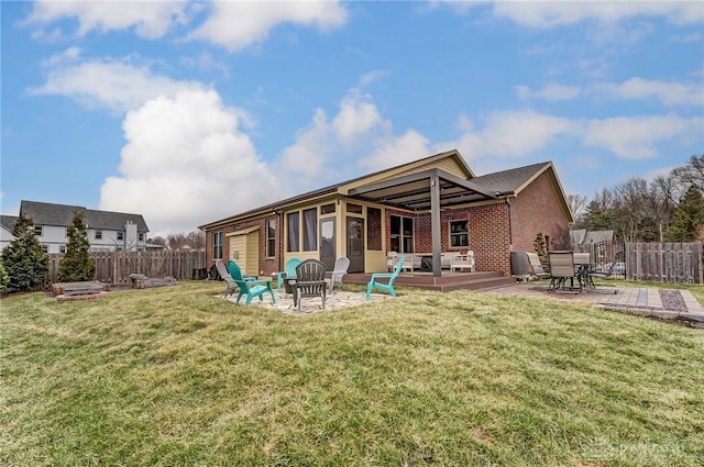 rear view of property featuring brick siding, an outdoor fire pit, and fence