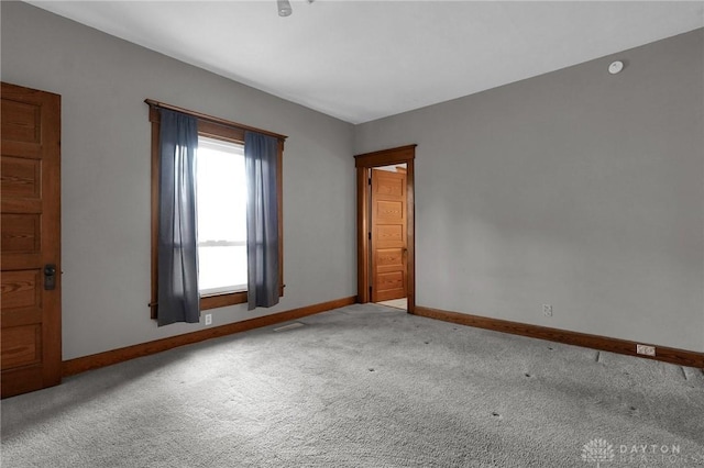 empty room featuring carpet floors, visible vents, and baseboards