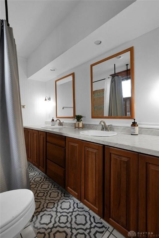 full bathroom with double vanity, toilet, and a sink