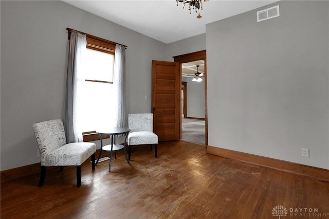 sitting room with baseboards, visible vents, and wood finished floors