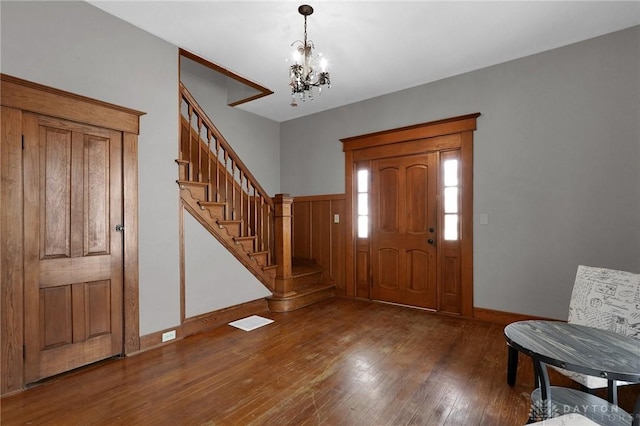 entryway with stairs, visible vents, a chandelier, baseboards, and hardwood / wood-style flooring