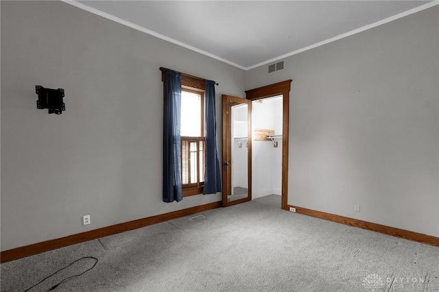 carpeted empty room featuring ornamental molding, visible vents, and baseboards