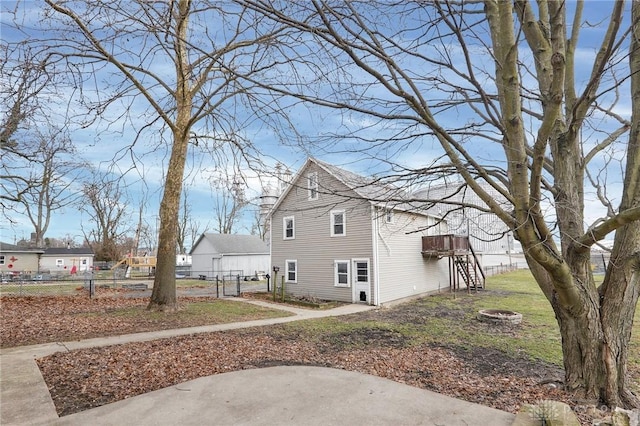 view of side of home featuring an outdoor fire pit and fence