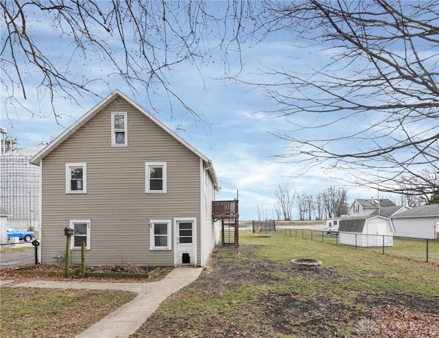 view of side of property featuring a deck, a lawn, a fire pit, and fence