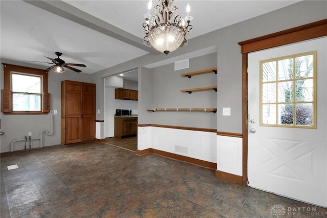 interior space featuring ceiling fan with notable chandelier, stone finish flooring, open shelves, and visible vents