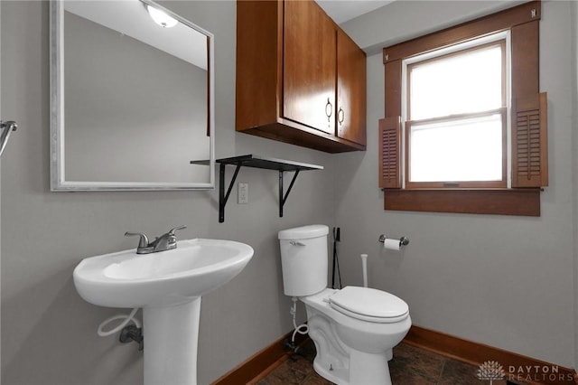 half bath featuring toilet and baseboards