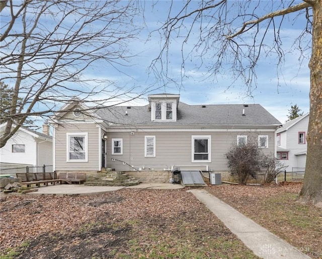 rear view of house with entry steps, central AC, a shingled roof, fence, and a patio area