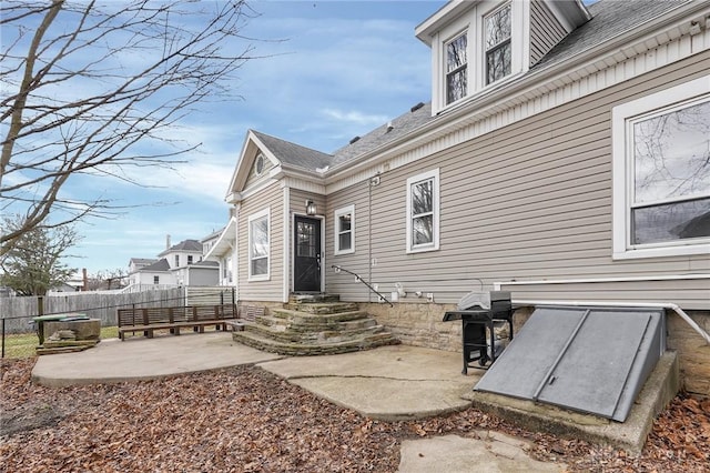 rear view of property with entry steps, fence, and a patio