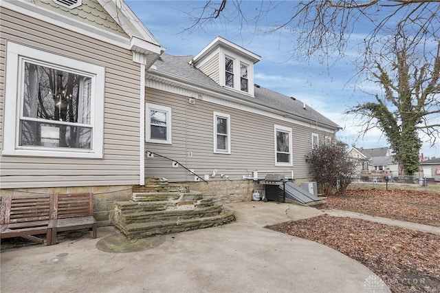 back of property featuring a shingled roof, fence, and a patio