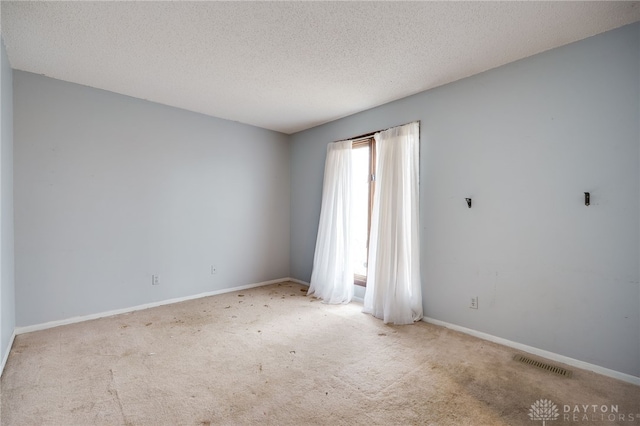 carpeted spare room featuring visible vents, a textured ceiling, and baseboards