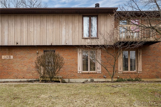 view of side of property featuring brick siding and a lawn