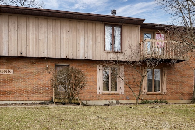 view of property exterior with brick siding, a yard, and a balcony