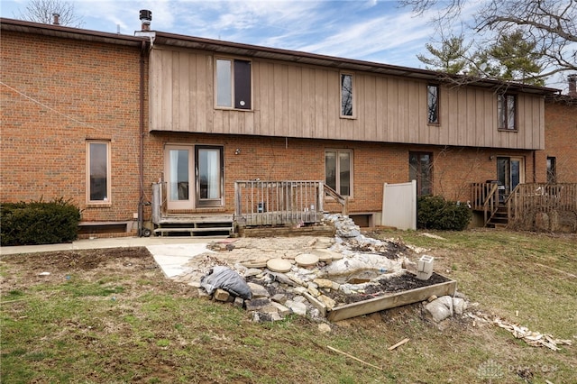 rear view of property with brick siding, a lawn, and a deck