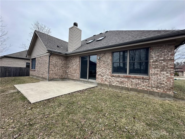 back of property featuring brick siding, a yard, a patio, a chimney, and fence