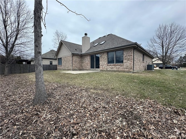 rear view of house featuring a chimney, fence, central air condition unit, a patio area, and brick siding