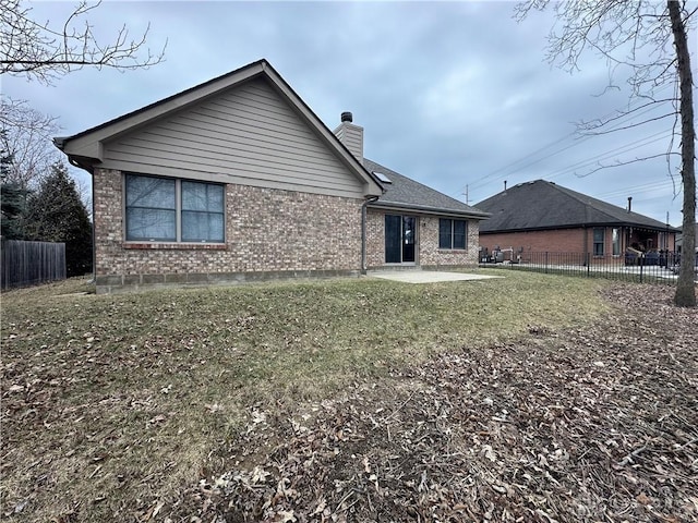 back of property with a patio, brick siding, a chimney, and fence