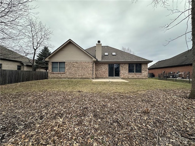 back of house with brick siding, a chimney, a shingled roof, and fence