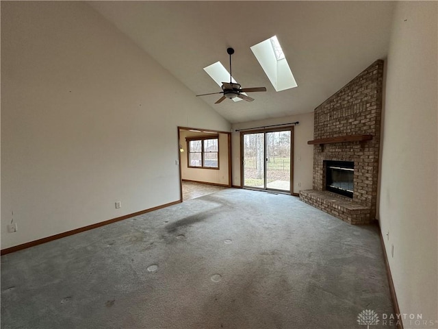 unfurnished living room featuring a skylight, baseboards, carpet, a brick fireplace, and high vaulted ceiling