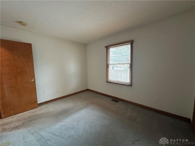 carpeted empty room with visible vents and baseboards