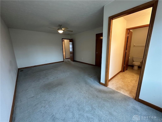 empty room with a ceiling fan, light colored carpet, a textured ceiling, and baseboards