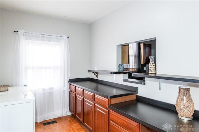 kitchen with washer / dryer, dark countertops, and visible vents