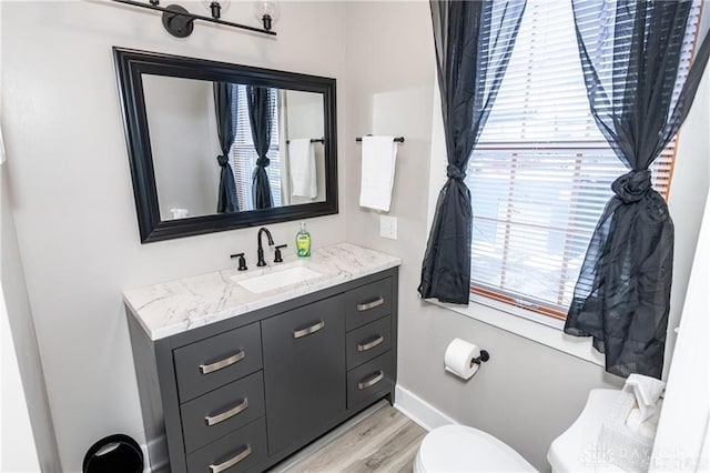 bathroom with baseboards, vanity, toilet, and wood finished floors