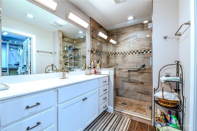 full bathroom featuring a walk in closet, recessed lighting, wood tiled floor, a shower stall, and vanity