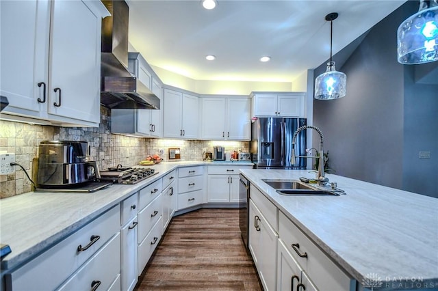 kitchen with wall chimney exhaust hood, appliances with stainless steel finishes, backsplash, and a sink