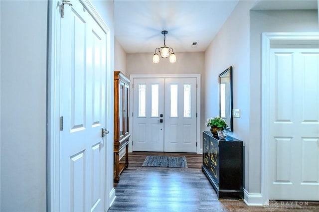 entryway featuring baseboards, dark wood-style flooring, visible vents, and a notable chandelier