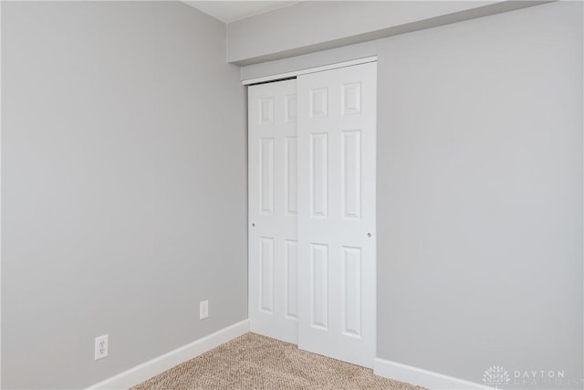 unfurnished bedroom featuring a closet, carpet flooring, and baseboards