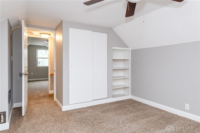 unfurnished bedroom featuring vaulted ceiling, a closet, carpet flooring, and baseboards