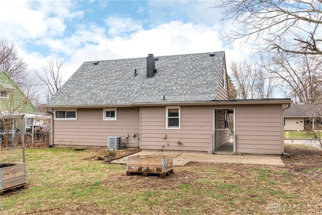 back of house featuring a shingled roof, a garden, a yard, and central AC