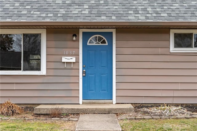 view of exterior entry featuring a shingled roof