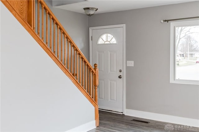 foyer featuring dark wood-type flooring, stairway, visible vents, and a healthy amount of sunlight