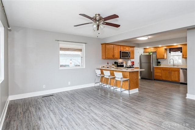 kitchen with baseboards, a peninsula, stainless steel appliances, light countertops, and a sink