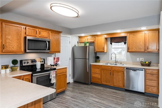 kitchen with wood finished floors, stainless steel appliances, a sink, and light countertops