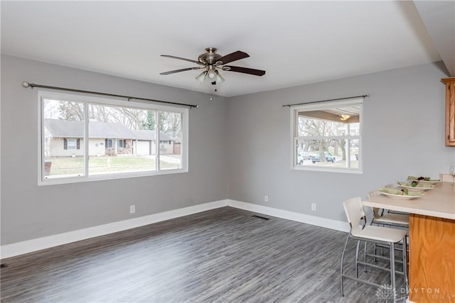 unfurnished office featuring dark wood finished floors, a ceiling fan, and baseboards