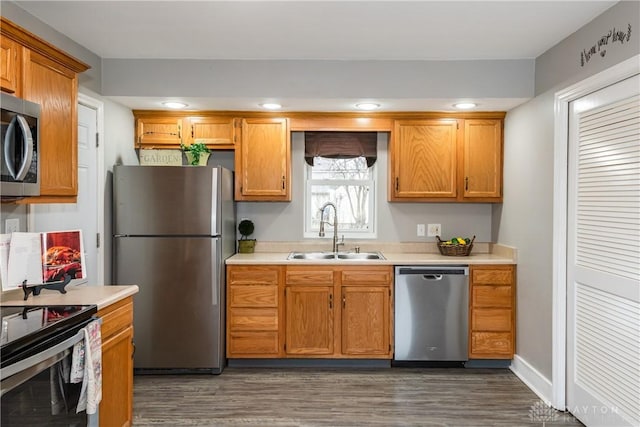 kitchen with stainless steel appliances, dark wood finished floors, a sink, and light countertops