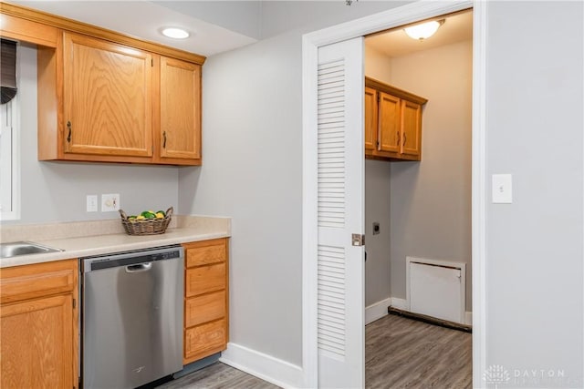 kitchen featuring a sink, wood finished floors, baseboards, light countertops, and stainless steel dishwasher