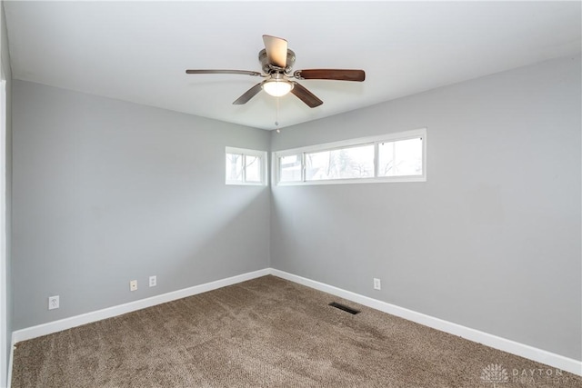 empty room featuring carpet floors, visible vents, baseboards, and a ceiling fan