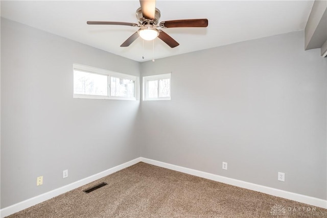 empty room with ceiling fan, carpet flooring, visible vents, and baseboards