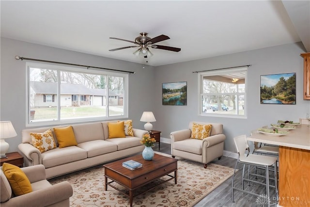 living room with ceiling fan, baseboards, and wood finished floors